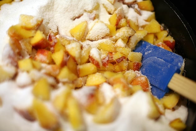 peaches and sugar in a deep pan ready to be processed