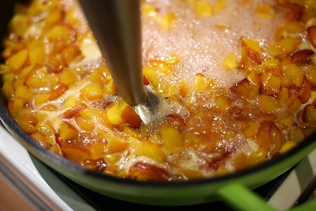 using an immersion blender to blend the jam