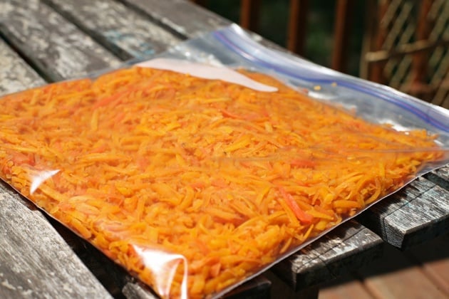 Measuring shredded carrots and transferring to a bowl. 
