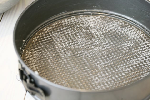 Coating a spring pan in butter. 