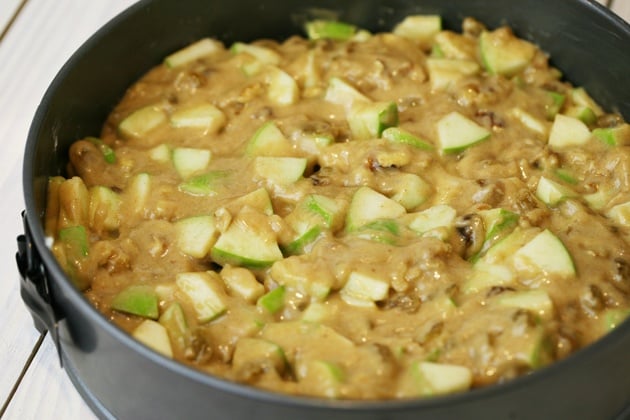 Adding the apple cake batter to the spring pan. 