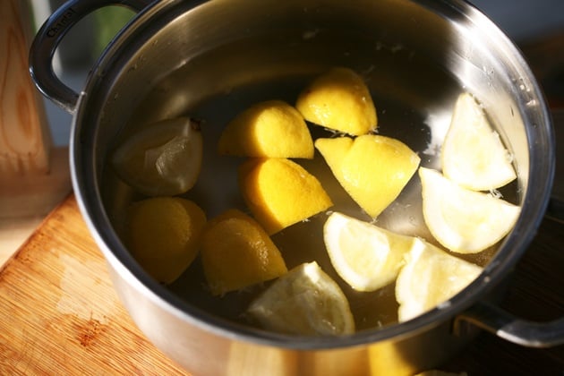 Adding lemon peels to a pot with water. 