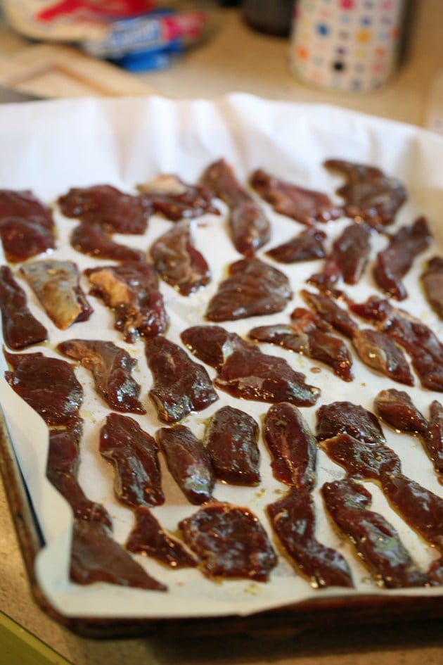 Laying the deer meat strips in one layer on a baking sheet.