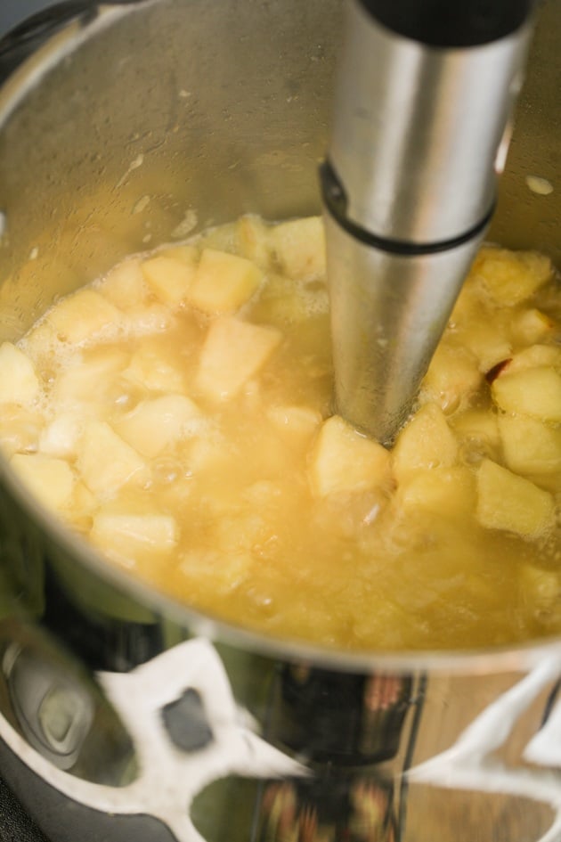 Using an immersion blender to puree the apples.