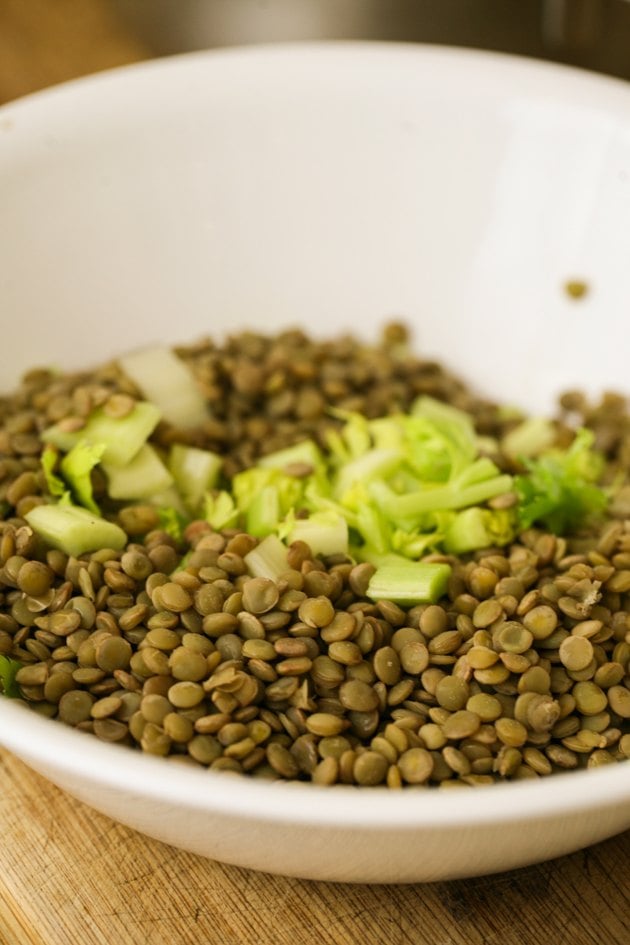 Adding lentils and celery to salad bowl.