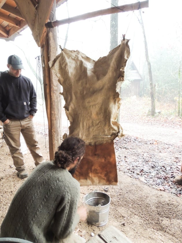 Starting the smoking fire under the hanging hides. 