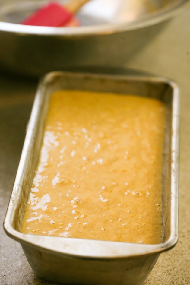 Transferring pumpkin bread batter to loaf pan.