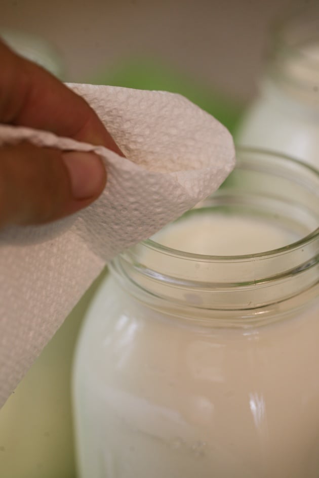 Cleaning the rim of the jar with a paper towel.