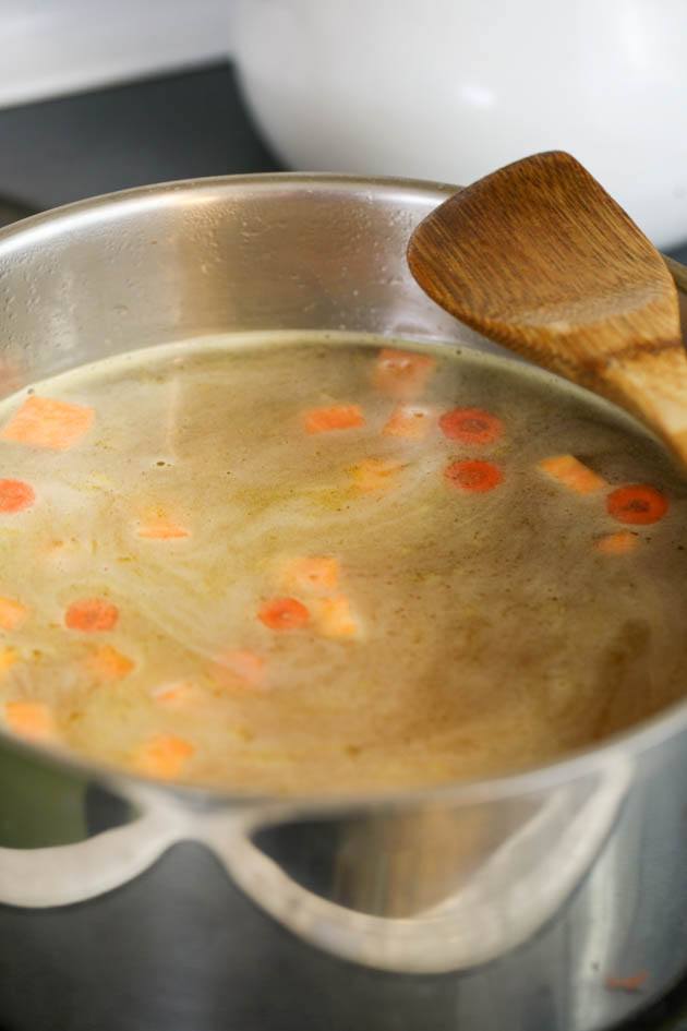 Adding chicken broth to the pot. 