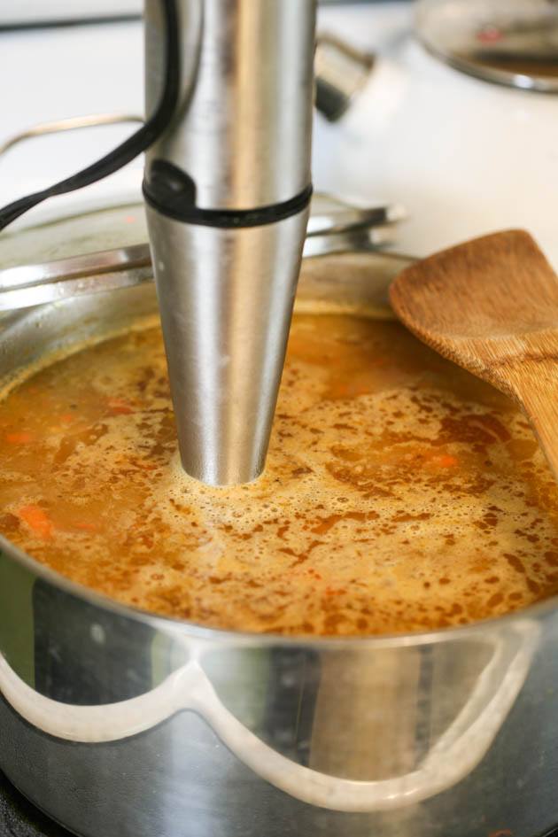 Using an immersion blender to puree the soup. 