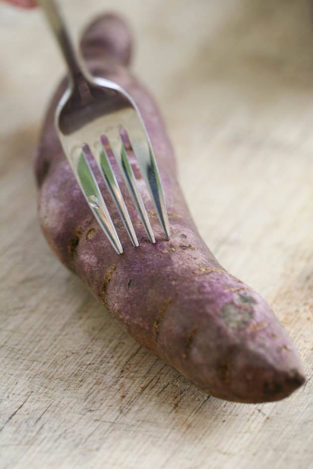 Making little holes in the sweet potato with a fork.