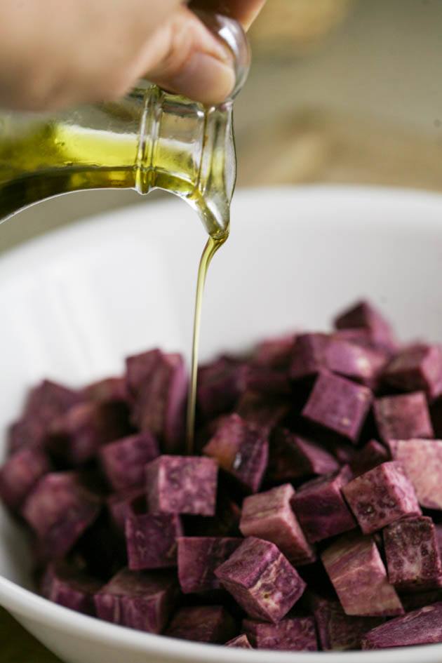 Adding olive oil to diced purple sweet potatoes.