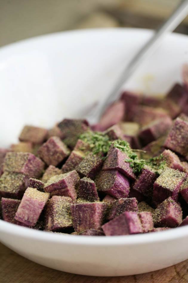 Adding seasonings to diced purple sweet potatoes.