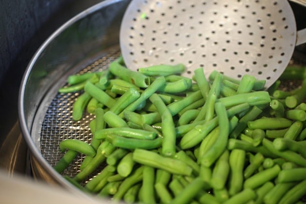 Lowering the blanched beans into an ice bath.