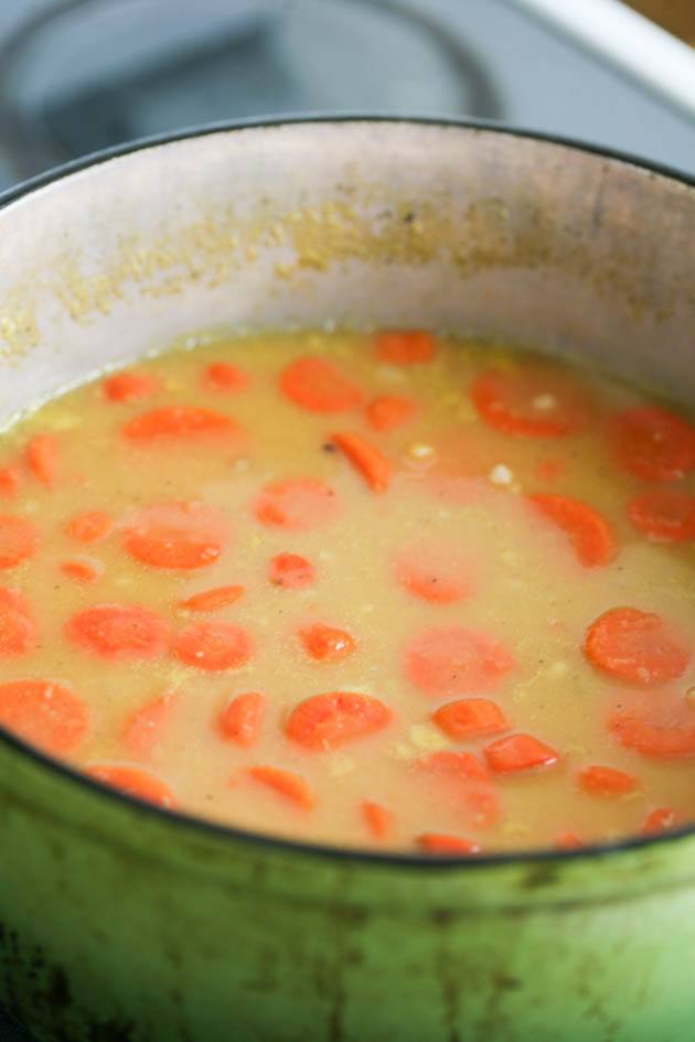 Adding carrots and stock to the soup.