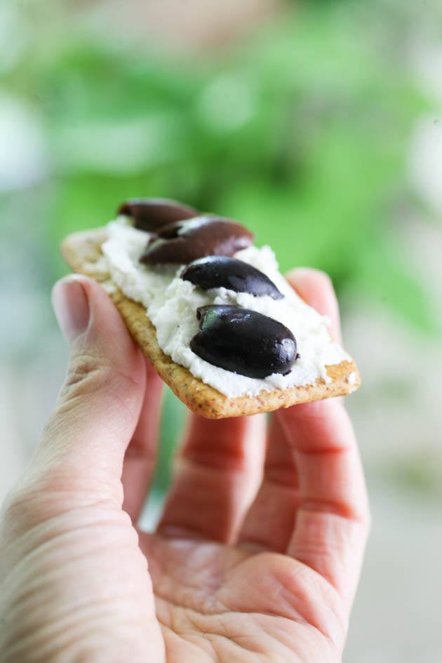 Goat cheese on a cracker with olives.