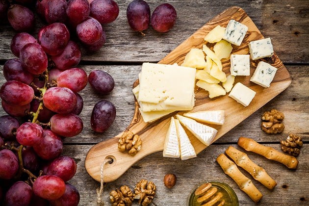 Cheese and fruit on a wooden board.