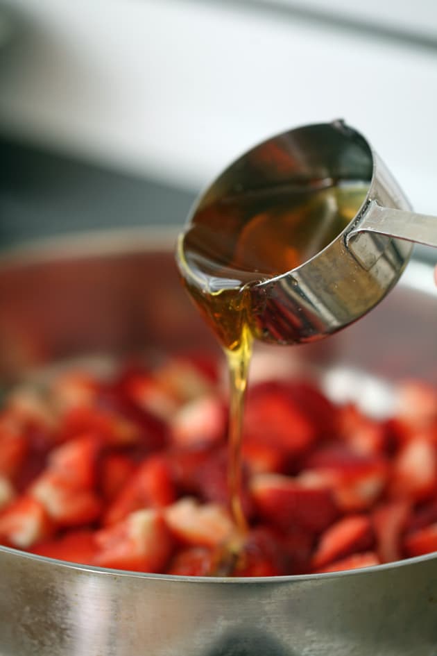 Adding honey tothe strawberries