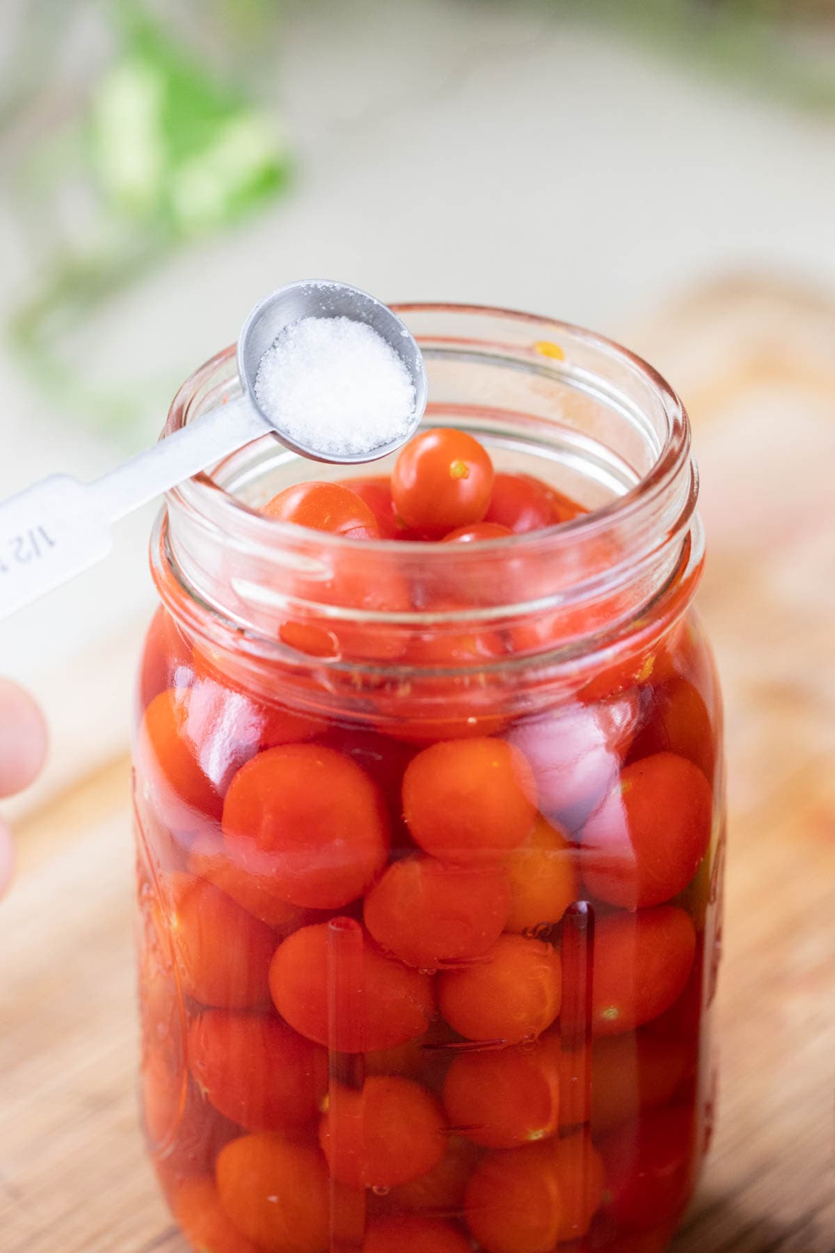 Adding citric acid and boiling water to the jars of cherry tomatoes.