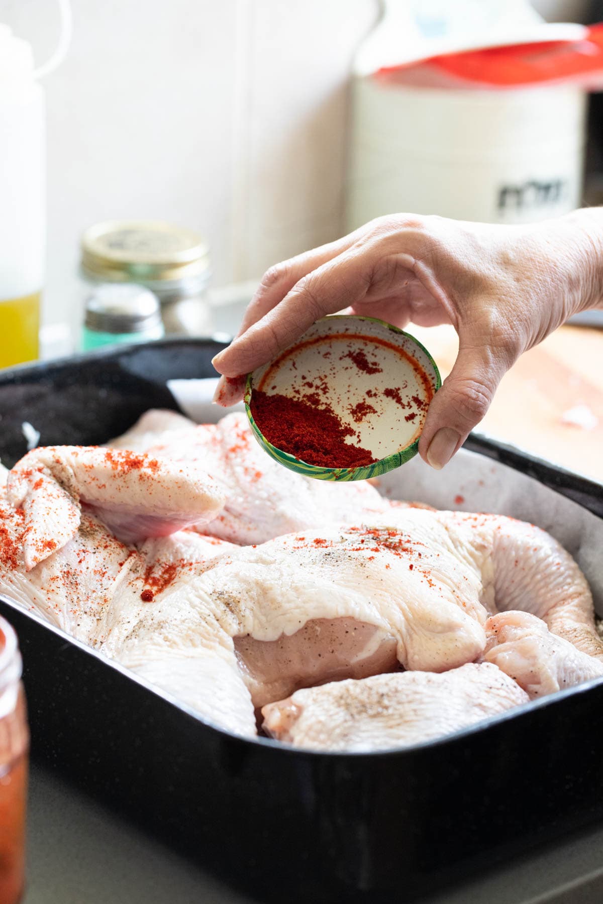Seasoning the chicken with paprika. 