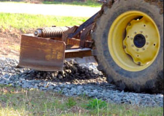 a tractor with a box blade spreading gravel