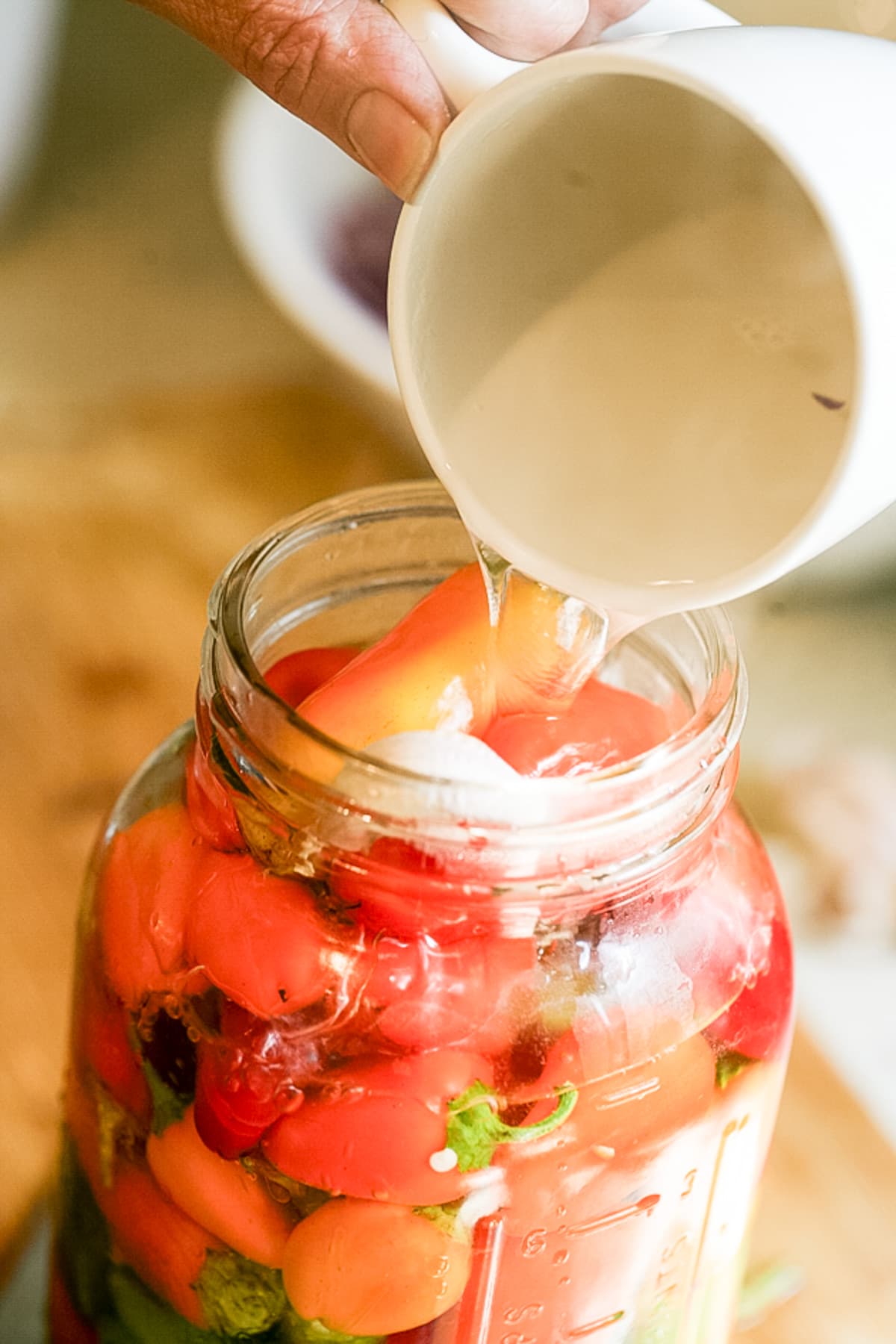 adding brine to the jar of peppers