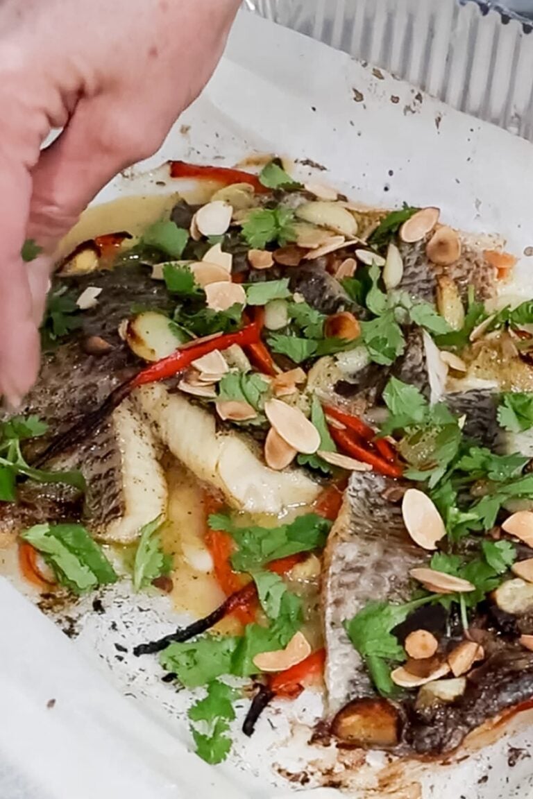 garnishing the oven baked tilapia with cilantro and almonds